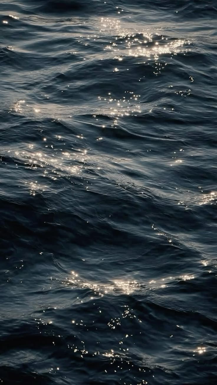 Superfície do mar com pontos de luz brilhando sobre as ondas